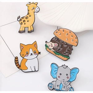Detailed view of colorful giraffe, cat, hedgehog and elephant enamel pins on a white background