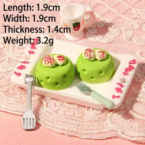 Macro shot of miniature green mousse cakes with roses on a tray and strawberry teacup