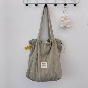 Detail of sage green pleated tote bag with yellow ribbon and lamb plush charm