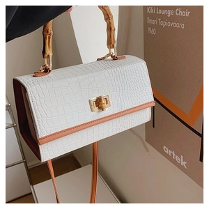 Close-up of white crocodile pattern handbag with bamboo handle and golden clasp hardware