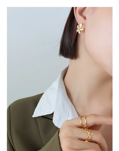 Detail of 18k gold plated petal earrings and geometric chain ring on a female model