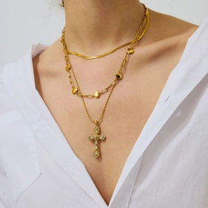 Detail einer mehrlagigen goldenen Edelstahlhalskette mit Zirkon-Kreuz und Herzanhänger