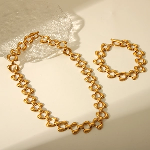 Flat lay of gold trapezoid link necklace and bracelet set with T-bar toggle clasp