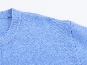 Dettaglio dello scollo a girocollo a coste e della morbida trama a maglia blu chiaro