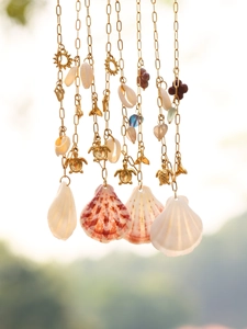 Detail of a golden ocean theme necklace with turtle pendants and natural sea shells