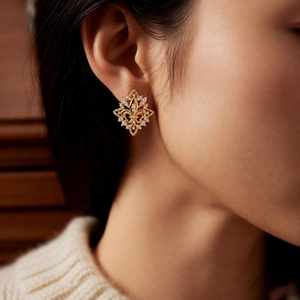 Close-up of 18k gold plated rhombus stud earrings with zircons on model ear