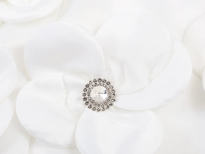 Dettaglio macro di un fiore in raso bianco con spilla in strass e cristallo scintillante