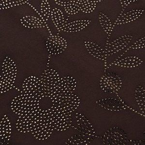 Détail du motif floral en strass dorés sur le tissu marron foncé de la robe moulante