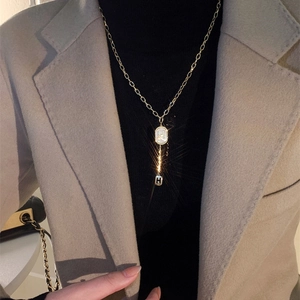 Gros plan d'un collier doré géométrique avec pendentif H et nacre sur le mannequin