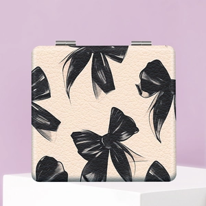 Detail of square beige leather makeup mirror with black bow patterns on a pedestal