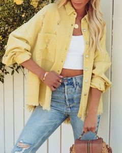 Detail of yellow vintage denim jacket featuring distressed holes and frayed raw edges
