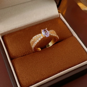 Detail eines goldenen Rings mit ovalem lila Zirkon und strukturierter Ringschiene