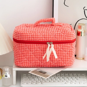 Close-up of red checkered quilted makeup bag with ribbon puller on a vanity table