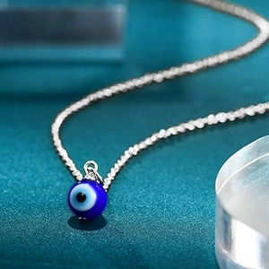 Close-up of the evil eye amulet pendant with blue layered details on a silver chain