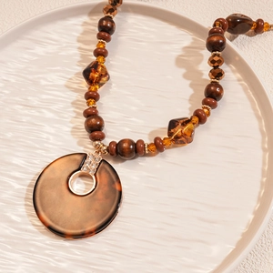 Détails d'un collier en perles de bois acrylique avec pendentif rond évidé léopard