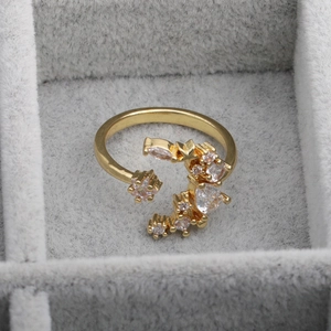 Close-up of adjustable gold star and flower ring with clear zircons in a velvet box