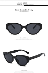 Detailed view of glossy black cat-eye sunglasses with metal rivets and grey lenses