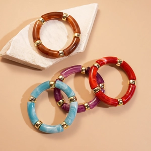 Vue détaillée de bracelets géométriques en acrylique avec entretoises dorées sur roche
