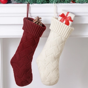 Red and cream knitted Christmas stockings hanging on a white fireplace mantle with gifts