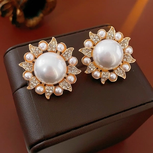 Macro shot of sun flower pearl earrings with crystals on a dark jewelry box