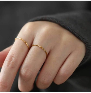 Detail of minimalist gold titanium ring with a tiny zircon, shown in a cozy hand-worn scene