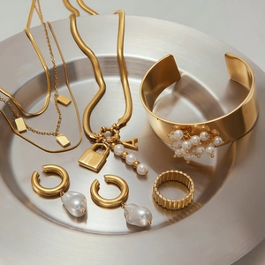 Détail d'un ensemble de bijoux en acier doré avec perles baroques sur un plateau d'argent