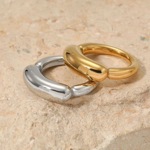 Minimalist thick band rings in gold and silver finish on a natural stone surface