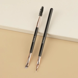 Dual-ended eyebrow brush and eyeliner brush with rose gold ferrule on a step display