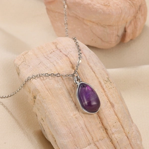 Macro view of water drop purple crystal pendant on 18K gold plated chain