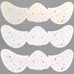 Close-up of gold, silver, and pink star freckle tattoo stickers on a gray background