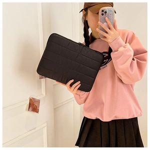 Close-up of black quilted puffer laptop sleeve with protective padding and zipper