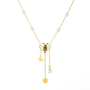 Detail of gold necklace with bee pendant featuring butterfly flower and pearl tassels