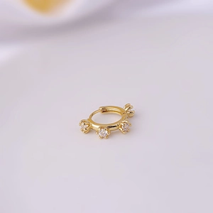 Detailed close-up of a gold-plated copper ear cuff set with three sparkling cubic zirconia