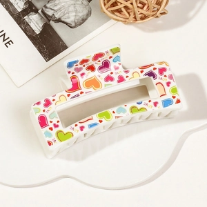 Detail of an ivory rectangular hair claw clip with colorful love hearts and love text