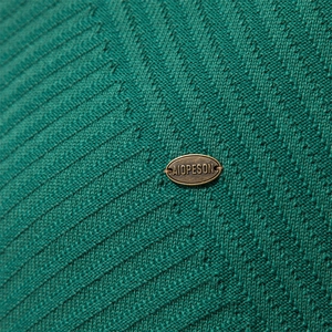 Close-up of emerald green knit sweater showing fine twill texture and metal logo