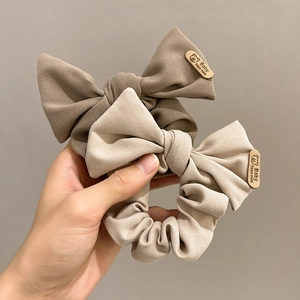 Detailed view of beige and brown fabric bow scrunchies with engraved wooden baby tags