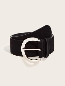Détail d'une large ceinture noire en daim avec une boucle en D argentée sur fond beige