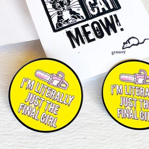 Detailed close-up of yellow horror movie lover enamel pins featuring pink chainsaw design
