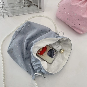 Detail of light blue sequin drawstring bucket bag showing interior space and pearl strap