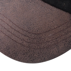 Macro shot of dark brown distressed leather brim with triple stitching on a baseball cap