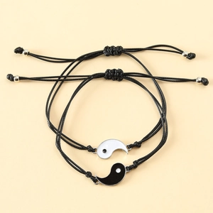 Yin Yang cord bracelets in black and white with adjustable woven straps on yellow background