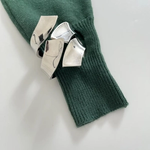 Irregular silver geometric bangle styled over a green knit sweater sleeve for women