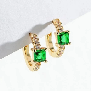 Macro detail of gold hoop earrings with square emerald zircon and pavé crystal accents