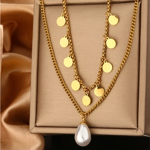Detail of gold double-layer necklace with circular charm and water-drop pearl pendant