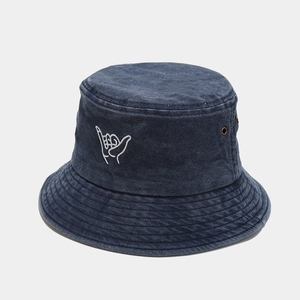 Detail of navy denim bucket hat with white shaka sign embroidery and metal eyelets