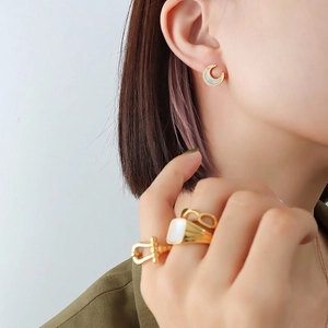Golden moon-shaped shell earrings and minimalist signet rings set in 18K gold plated steel