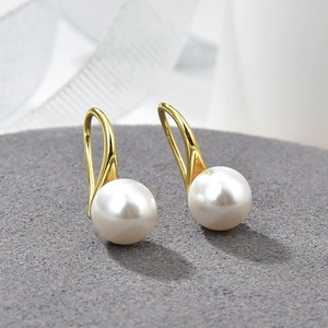 Elegant gold bow earrings with baroque pearls and cubic zirconia on white background