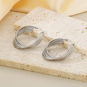 Silver twisted rope hoop earrings made of titanium steel on elegant beige stone