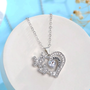 Détail du collier cœur argenté évidé avec motif papillon et gravure I love you chic