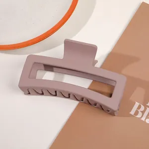 Close-up of a large matte grey-purple rectangular hair claw clip on a stylish table